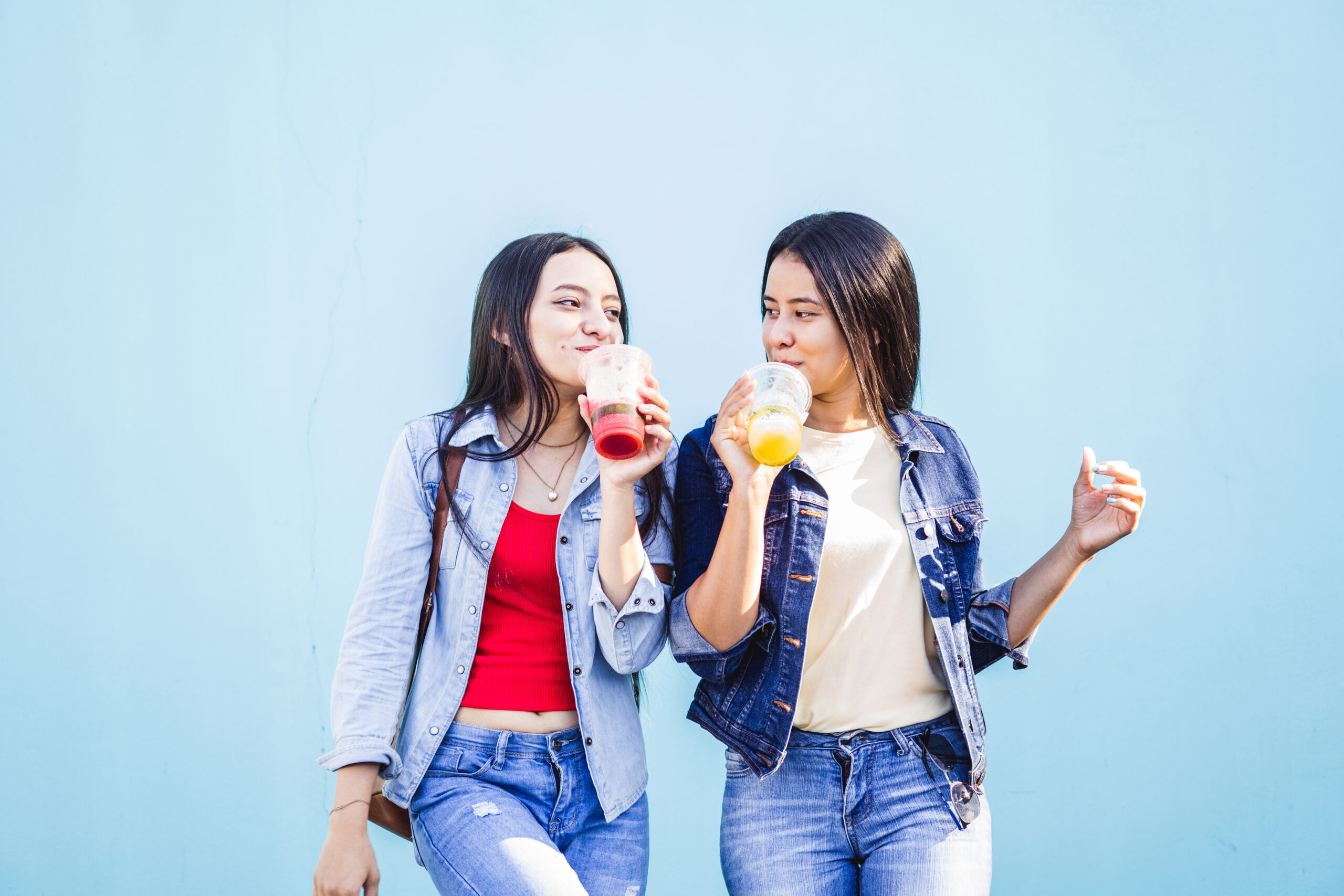 Hispanic female sisters drinking a juice